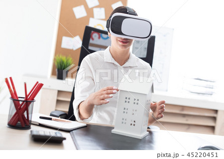 Young girl sitting in virtual reality glasses. Before her on the table is the layout of the house. Young girl sitting in virtual reality glasses. Before her on the table is the layout of the house. 45220451