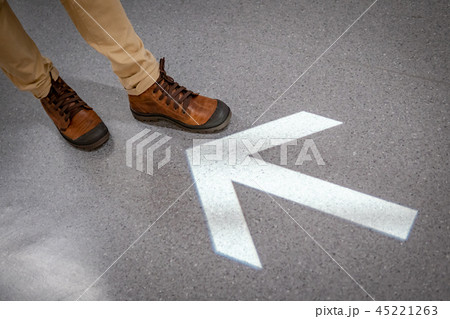 Male feet standing at the end of arrowhead sign 45221263