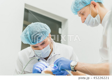 Doctor used microscope. Dentist is treating patient in modern dental office. Operation is carried 45226221