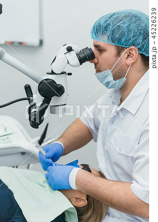 Doctor used microscope. Dentist is treating patient in modern dental office. Operation is carried 45226239