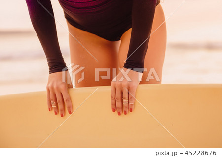 Surf girl with surfboard on beach at sunset Surf girl with surfboard on beach at sunset 45228676