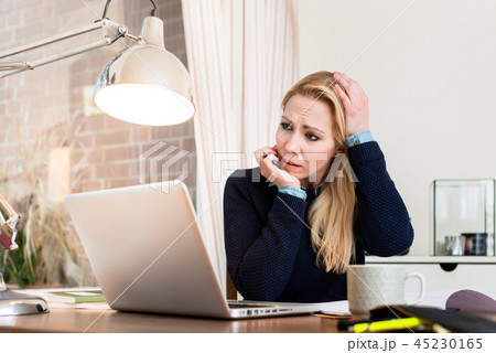 Worried woman looking at laptop Worried woman looking at laptop 45230165
