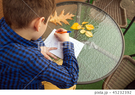 Boy is doing homework outdoors 45232392