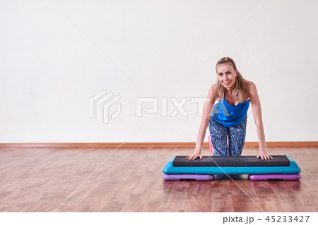 Young sportive woman exercising in gym using step platform, copy space. Young sportive woman exercising in gym using step platform, copy space. 45233427