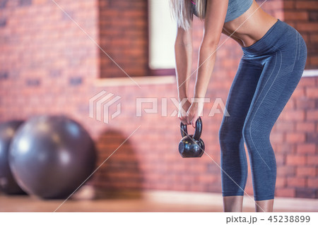 Woman with slim body in gym holding a kettlebell. 45238899