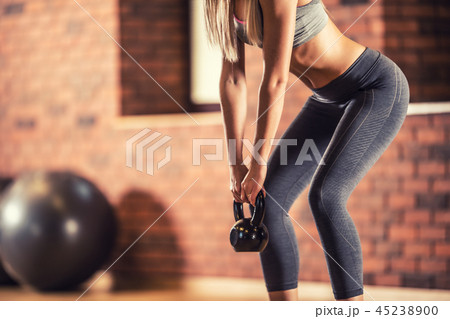 Woman with slim body in gym holding a kettlebell. 45238900