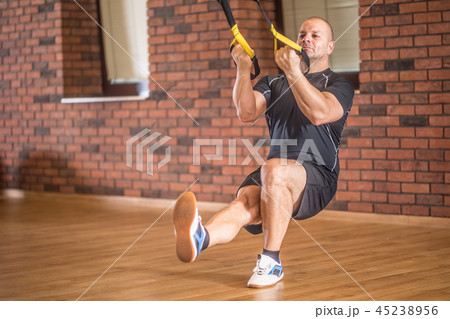 Strong man exercising with trx facilities in gym. Strong man exercising with trx facilities in gym. 45238956