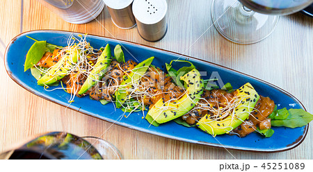 Delicious salmon tartare garnish with avocado on blue plate Delicious salmon tartare garnish with avocado on blue plate 45251089