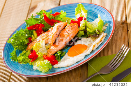 Tasty breakfast with trout, egg, pepper and lettuce at plate on table Tasty breakfast with trout, egg, pepper and lettuce at plate on table 45252022