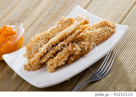 Tasty fried chicken fingers from fillet in sesame at plate on table 45252115