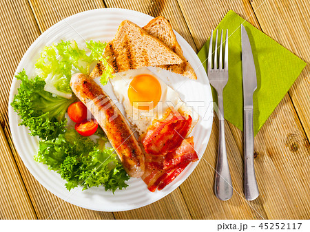 Tasty breakfast of sausage, bacon, scrambled eggs 45252117