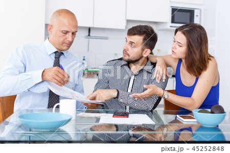 Upset young man and wife signing agreement papers with social worker 45252848