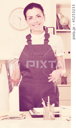 Cheerful female cleaning furniture in office 45253233