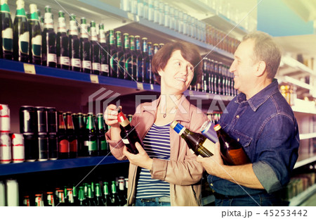 Portrait of an elderly couple buying a beer at the grocery store Portrait of an elderly couple buying a beer at the grocery store 45253442