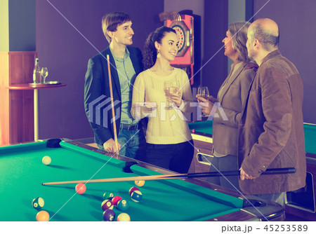 Mature and young couples hanging out in billiard club together Mature and young couples hanging out in billiard club together 45253589