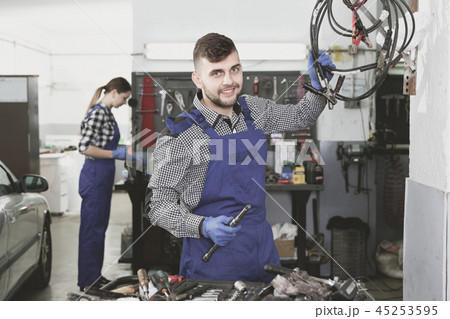 Man master is choosing instruments for work in workshop. 45253595