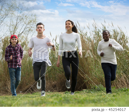 Portrait of four teenagers running on field Portrait of four teenagers running on field 45254017