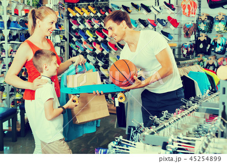 Cheerful young parents giving skateboard to their son in school age Cheerful young parents giving skateboard to their son in school age 45254899