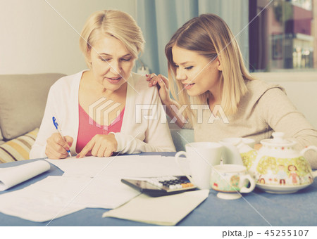 Daughter helps mother to lead home accounting Daughter helps mother to lead home accounting 45255107