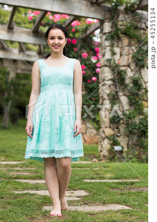 portrait of young woman in dress near roses in a garden 45255134