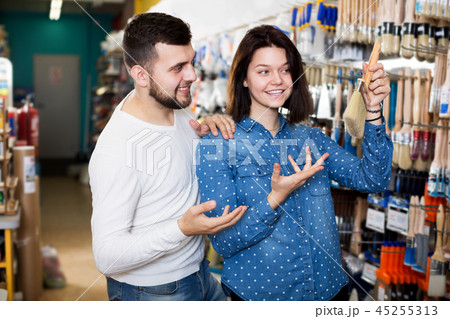 Couple examining various painting brushes 45255313