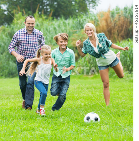 Family of four playing football on field 45255614