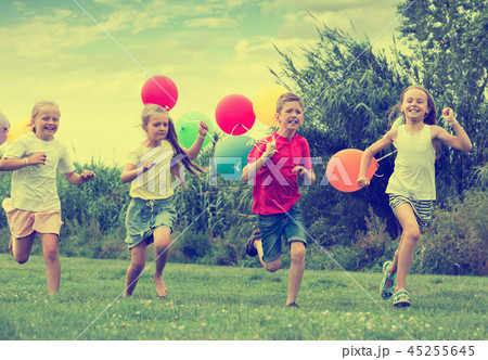Playful kids running with balloons Playful kids running with balloons 45255645