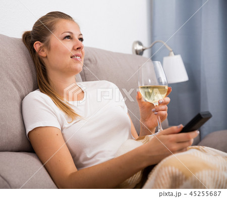Girl is resting with wine and watching TV Girl is resting with wine and watching TV 45255687