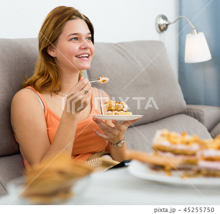 Cheerful female eating sweet cake at home 45255750