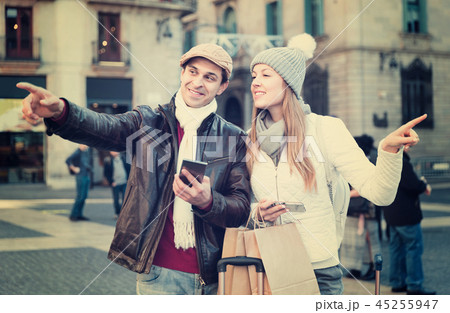 Couple at the historical city center with mobile phones pointing finger 45255947