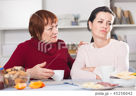Portrait of sad mature woman talking with daughter Portrait of sad mature woman talking with daughter 45256042