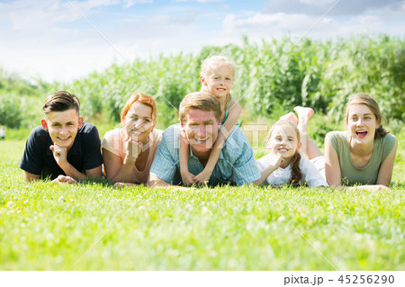 Portrait of friendly large family lying on green lawn outdoors Portrait of friendly large family lying on green lawn outdoors 45256290