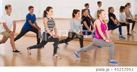 Teenage boys and girls with trainer stretching in dance hall 45257051