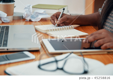 Crop businesswoman with tablet writing in notepad 45258816
