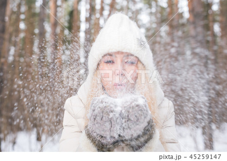 Christmas, holidays and season concept - Young happy blond woman blowing snow in the winter nature 45259147
