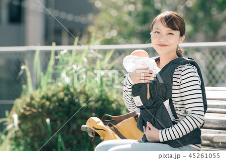 公園のベンチに座る子育てママ 日本人30代女性の写真素材