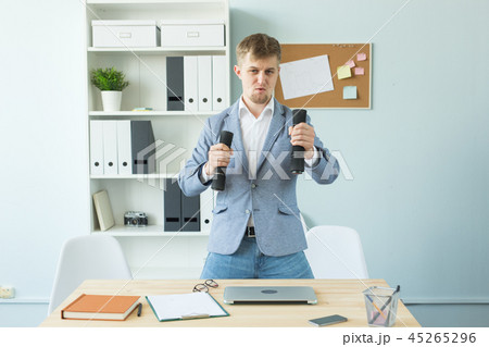 Business, fitness in office and people concept - handsome man in office holding dumbbell in hand 45265296