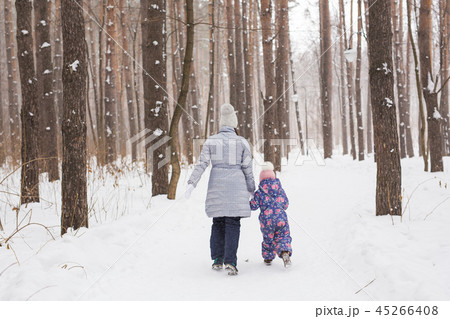 Winter, family and people concept - Mother is walking with her little daughter in snowy park, back Winter, family and people concept - Mother is walking with her little daughter in snowy park, back 45266408