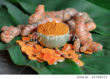 Turmeric roots and powder on background Turmeric roots and powder on background 45268914