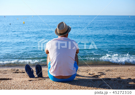 A young man in a straw hat sitting on the beach A young man in a straw hat sitting on the beach 45272310