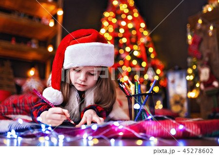 Funny girl in Santa hat writes letter to Santa Funny girl in Santa hat writes letter to Santa 45278602
