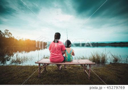 Mother and daughter sit and relax by the lake. 45279769