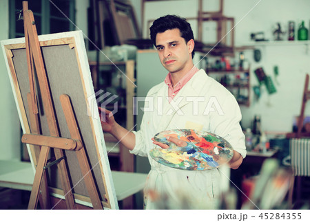 Man near easel painting on canvas 45284355