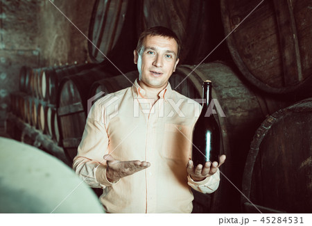 man with bottle of wine in winery cellar. 45284531