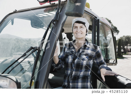 Confident female farm owner driving tractor 45285110