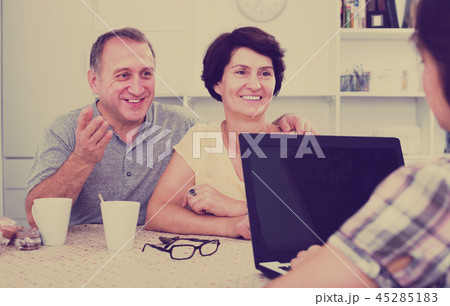Smiling senior couple listening to young woman Smiling senior couple listening to young woman 45285183