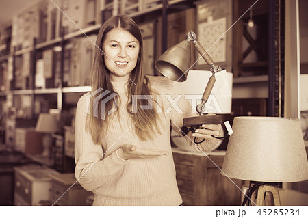 Portrait of cheerful woman buyer choosing modern lamp in furniture shop Portrait of cheerful woman buyer choosing modern lamp in furniture shop 45285234