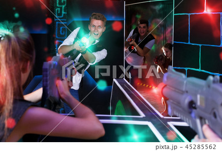 Excited people playing enthusiastically laser tag game Excited people playing enthusiastically laser tag game 45285562