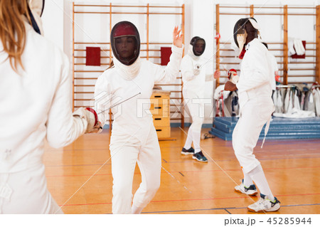 Two female fencers exercising movements in duel at fencing room 45285944