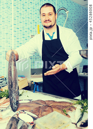 Smiling seller in black apron showing fish Smiling seller in black apron showing fish 45286008